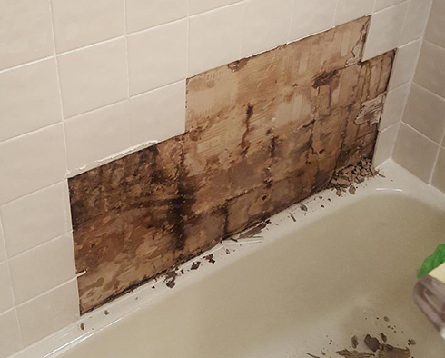 Water Damaged Drywall Backing in Shower on Left and on Right It's Repaired With Tiles and Grout